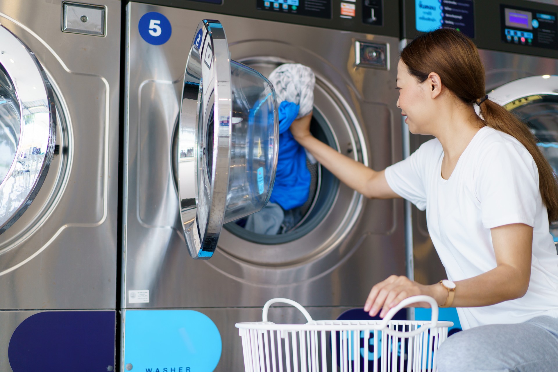 Woman using self-service washing machine.